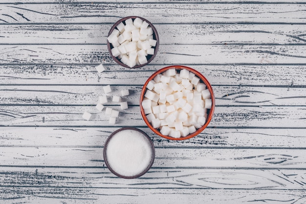 Flat lay white sugar in bowls on white wooden table. horizontal