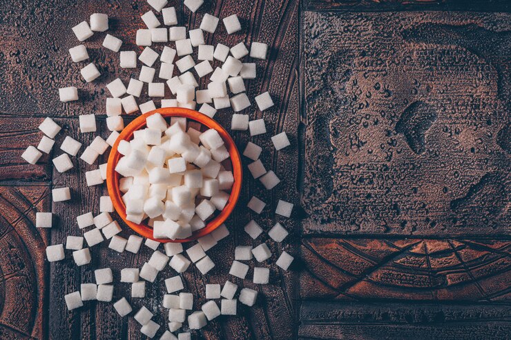 मुफ़्त फोटो flat lay white sugar cubes in orange bowl on dark wooden table. horizontal