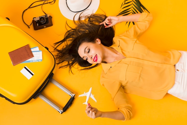 Flat lay of woman posing next to travel essentials