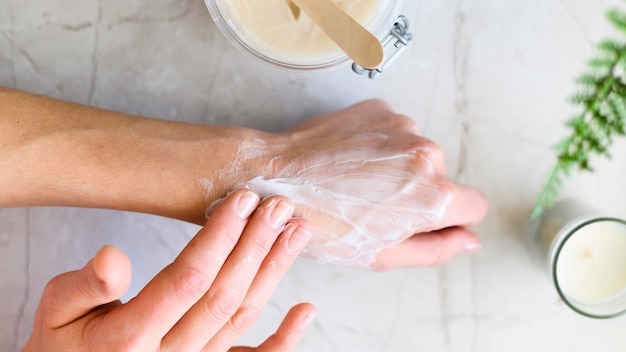 Flat lay of woman putting cream on her hands
