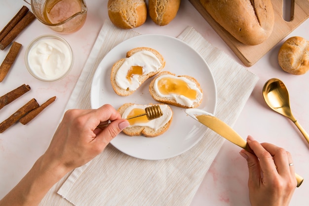 Flat lay woman spreading cream cheese on bread