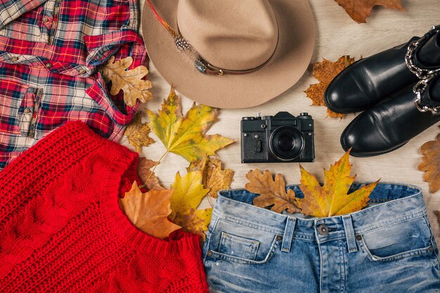Flat lay of woman style and accessories, red knitted sweater, checkered shirt, denim jeans, black leather boots, hat, autumn fashion trend, view from above, clothes, yellow leaves