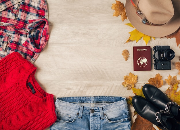 Flat lay of woman style and accessories, red knitted sweater, checkered shirt, denim jeans, black leather boots, hat, autumn fashion trend, view from above, vintage photo camera, passport