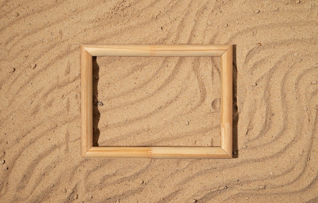 Free photo flat lay wooden frame on sand