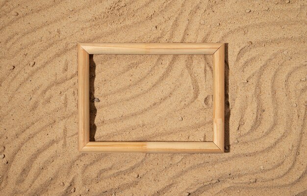 Flat lay wooden frame on sand