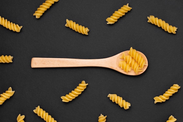 Flat lay wooden spoon with uncooked fusilli