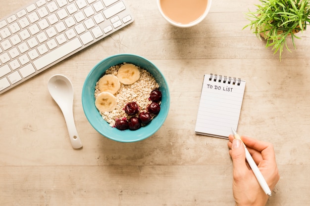 Flat lay and writing in notebook near bowl with oats and fruits