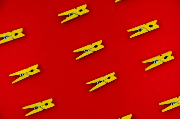 Flat-lay yellow clothes pins on red background