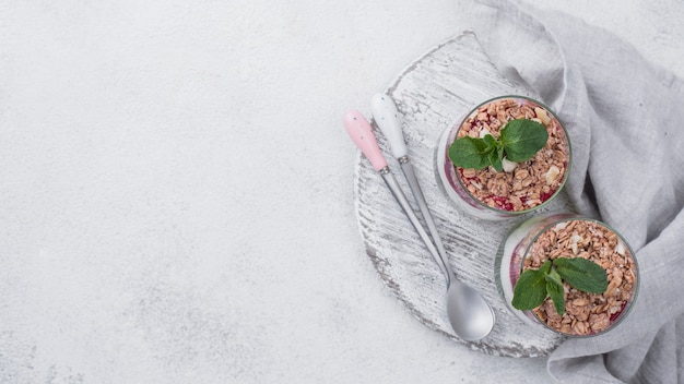 Free photo flat lay of yogurt glasses with cereal and mint