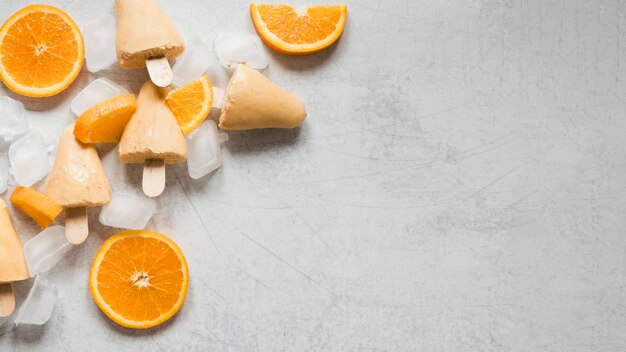 Flat lay of yummy orange flavored popsicles with copy space