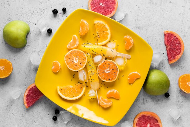 Flat lay of yummy popsicles with fruits and ice