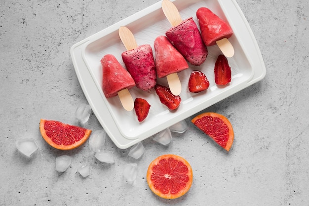 Flat lay of yummy popsicles with ice and red grapefruit