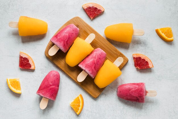 Flat lay of yummy popsicles with orange and red grapefruit