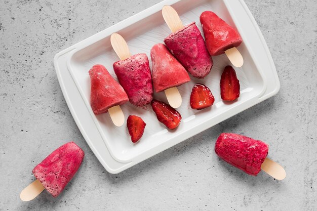 Flat lay of yummy popsicles with strawberries