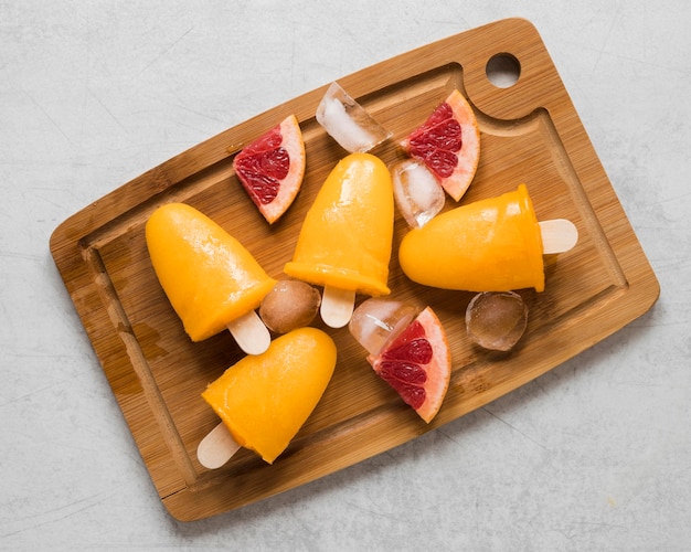 Flat lay of yummy red grapefruit flavored popsicles on chopping board