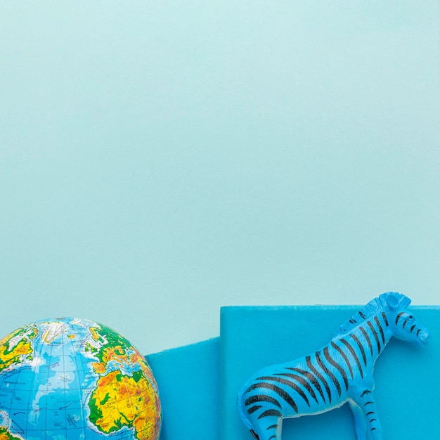 Flat lay of zebra figurine with planet earth and books for animal day