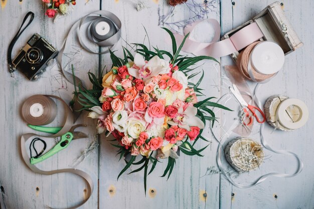 Flatlay of orange wedding bouquet and ribbons on working table