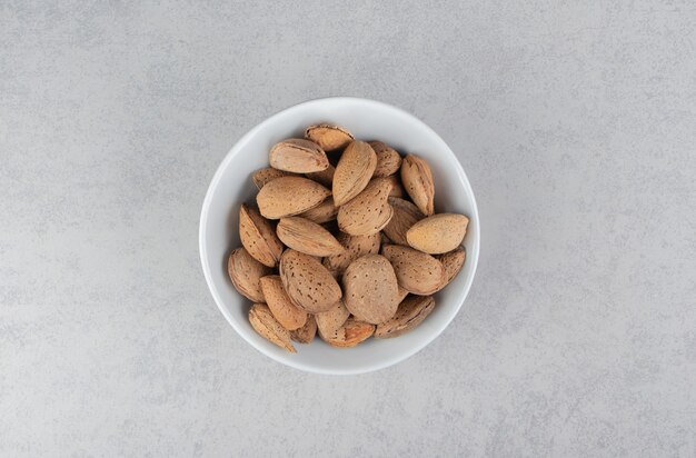 Flavorful almonds in the bowl, on the marble surface