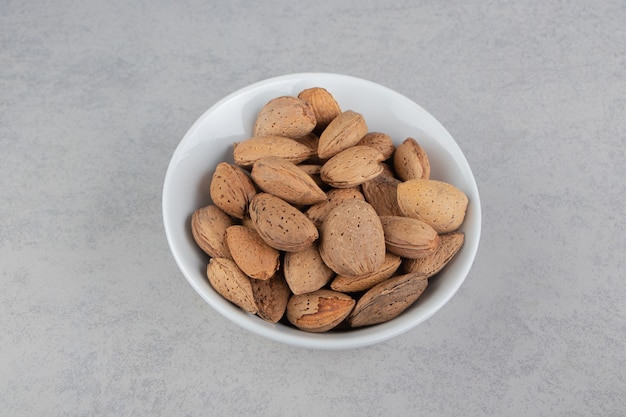 Flavorful almonds in the bowl, on the marble surface