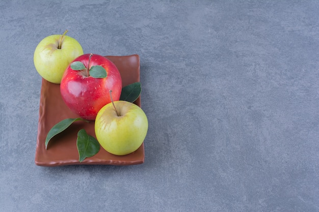 暗い表面の木製プレートに葉を持つ風味豊かなリンゴ