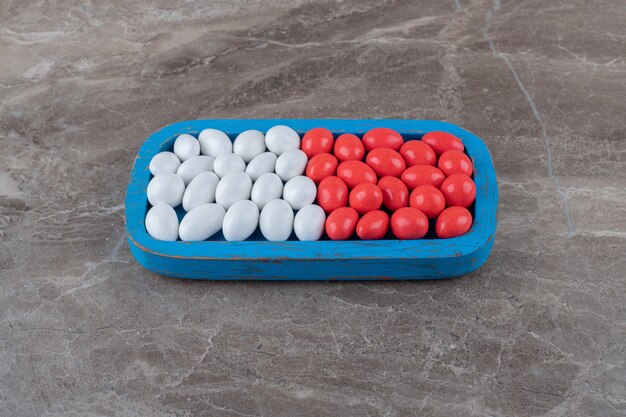 Flavorful candies on the blue tray on the marble surface