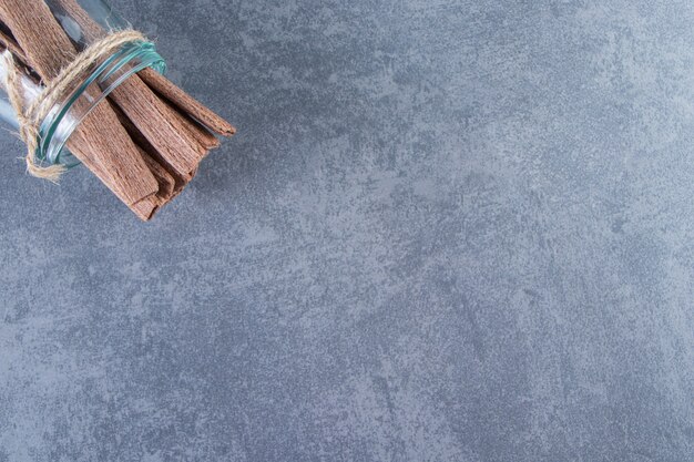 대리석 표면에 있는 항아리에 맛있는 초콜릿 웨이퍼 롤