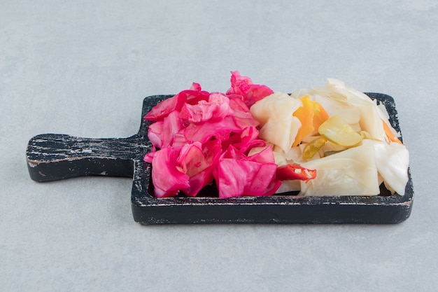 Flavorful chopped red and green pickled cabbage on the board on the marble surface