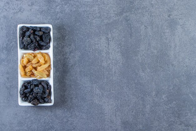 Flavorful raisins on a dish , on the marble background.