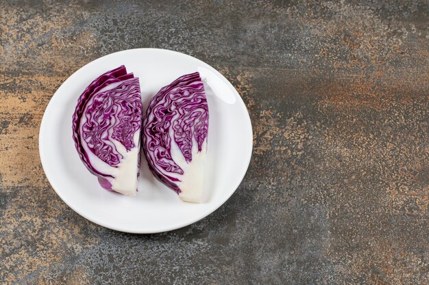 Flavorful red cabbage in the white plate on the marble surface