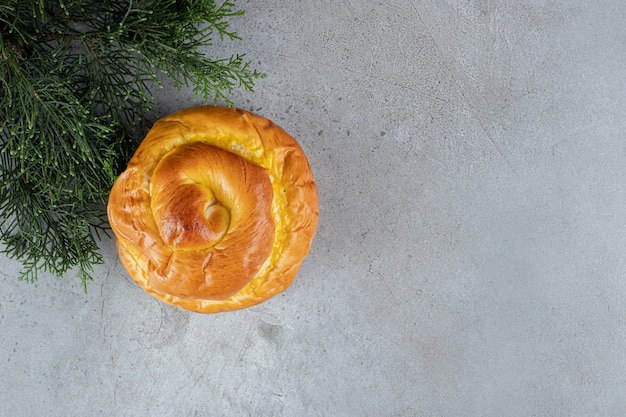 Flavorous bun and pine branch arranged on marble surface