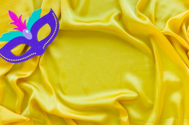Flay lay of carnival mask on yellow fabric with copy space