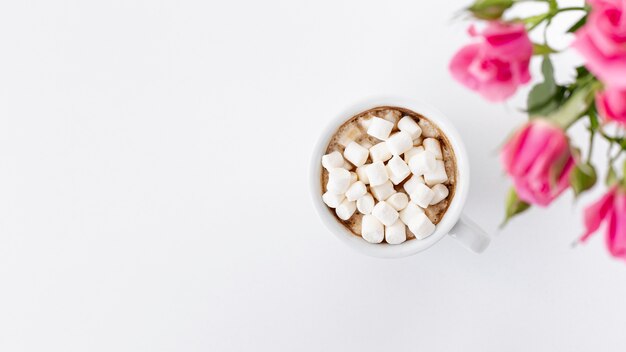 Flay lay of marshmallow cup with roses and copy space