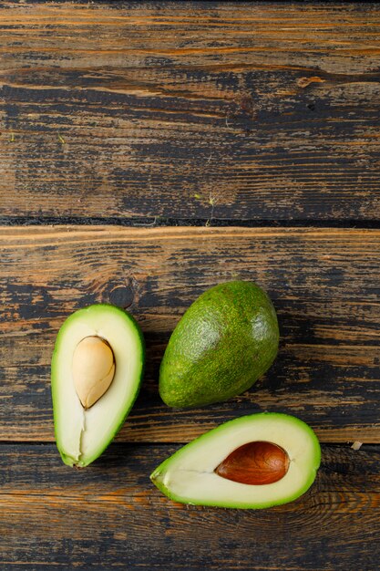 Fleshy avocado with halves high angle view on a old wooden table