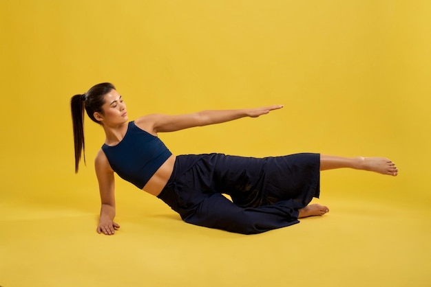 Flexible girl lying on side raising arm and leg