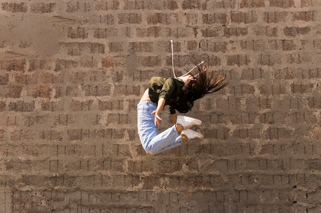 フレキシブルなモダンなスタイルの女性ダンサー、空気中でジャンプ