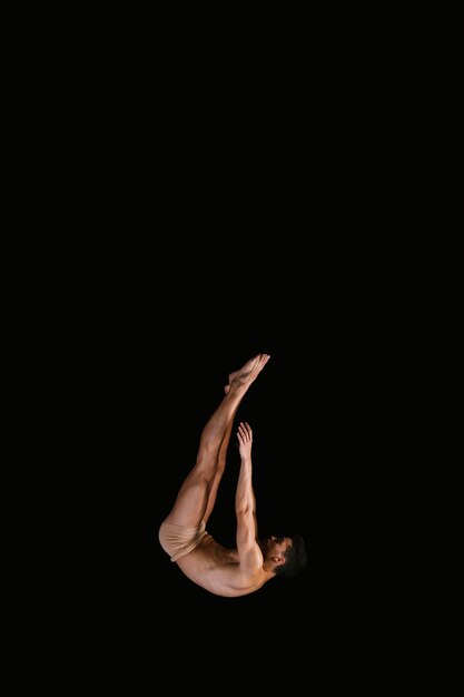 Flexible sportsman flying on black background