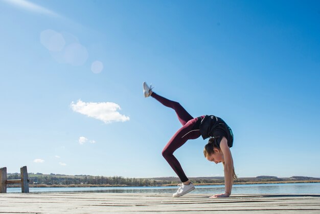 Flexible teenager exercising on pier
