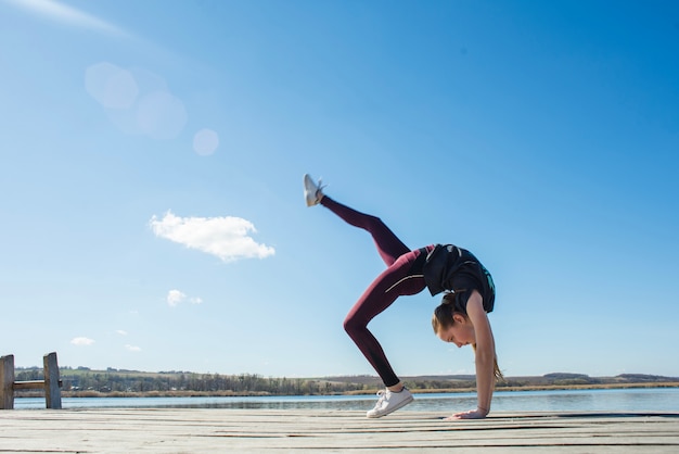 Flexible teenager exercising on pier