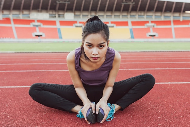 Foto gratuita donna flessibile seduta sulla pista di atletica