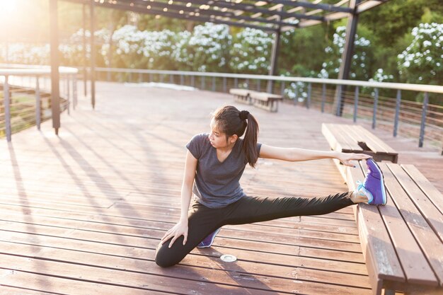 Flexible woman stretching with leg on a bench