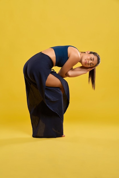Donna flessibile che torce corpo e braccia in asana di yoga indoor