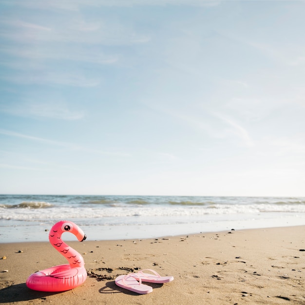 Free Photo flip flops and inflatable flamingo at the beach