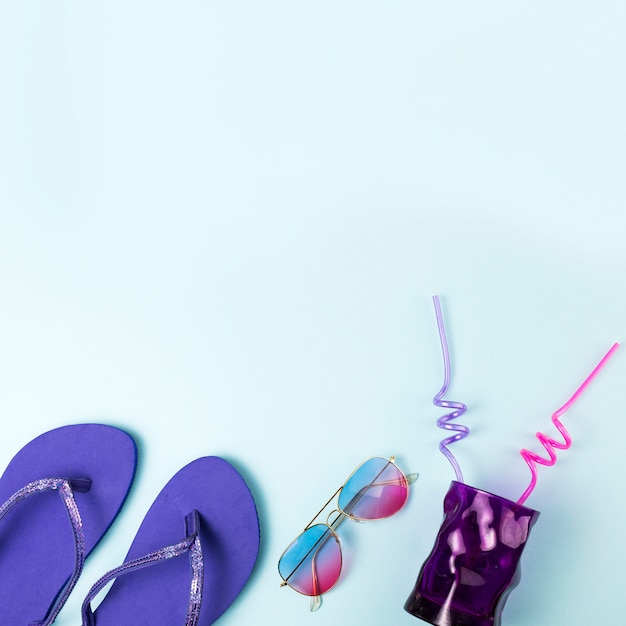 Flip flops near sunglasses and glass with straws