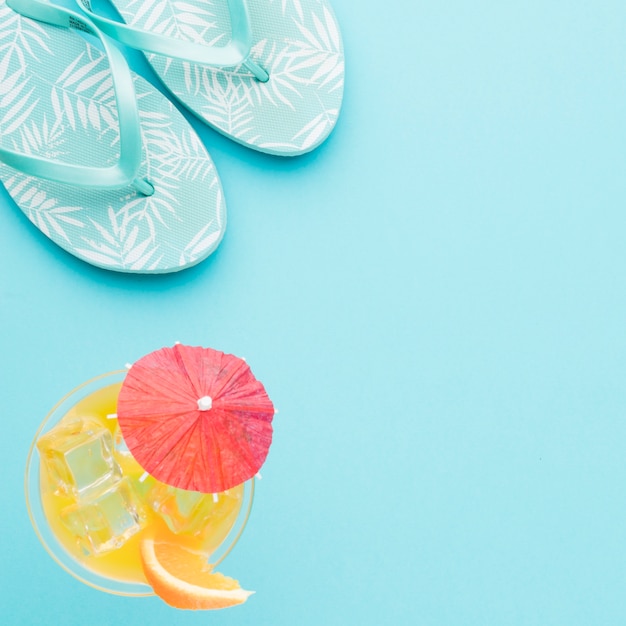 Flip-flops and refreshing cocktail on colored background