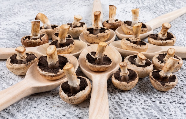 Foto gratuita funghi lanciati in cucchiai su una tabella grigia