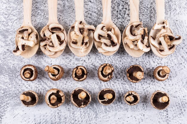 Flipped, sliced mushrooms in spoons on a gray table