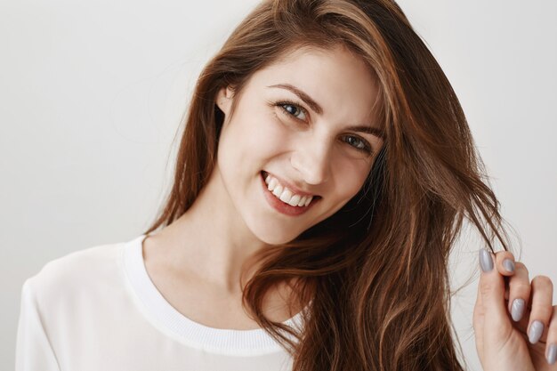 Flirty happy woman playing with hair and smiling