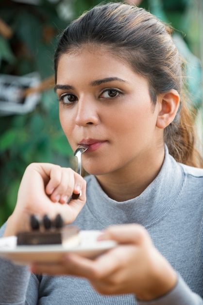 ケーキを食べてカメラを見ているふわふわの女性