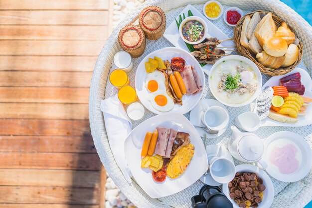 Floating breakfast set in tray with fried egg omelette sausage ham bread fruit milk juice coffee