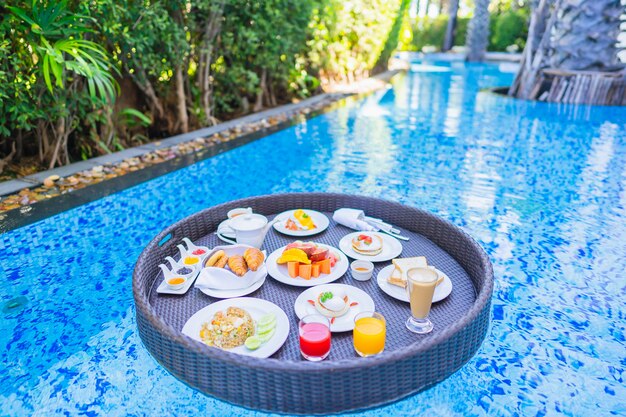 Floating breakfast set in tray with fried egg omelette sausage ham bread fruit milk juice coffee